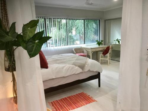 a bedroom with a bed and a large window at LILY LAMOND, T/House, outdoor shower, 5 min walk to the ocean, Airlie Beach in Airlie Beach