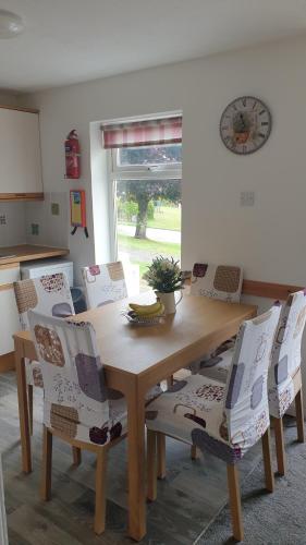 a dining room table with chairs and a clock on the wall at Rock Cottage in Callington