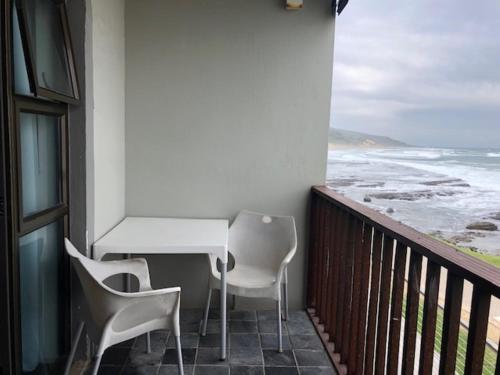 a balcony with a table and chairs and the ocean at Mitford Apartments in Morganʼs Bay