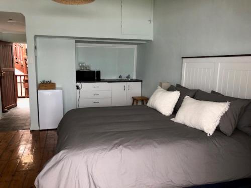 a bedroom with a large bed and a kitchen at Mitford Apartments in Morganʼs Bay