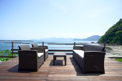 a group of chairs and a table on a deck overlooking the water at Rainbow Village（レインボーヴィレッジ） in Mihama