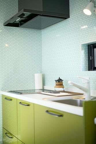 a kitchen with yellow cabinets and a black hood at Rainbow Village（レインボーヴィレッジ） in Mihama