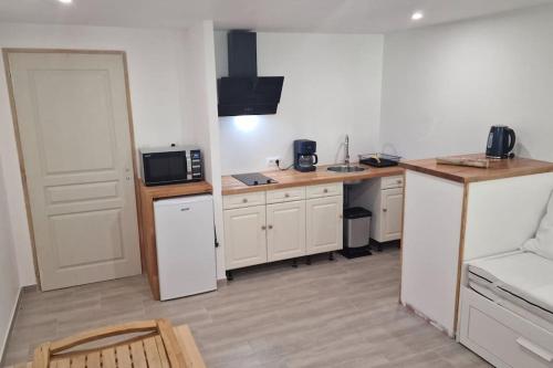 une cuisine avec des placards blancs et un comptoir avec un four micro-ondes dans l'établissement Ariège, agréable T2 en bord de rivière, à Vicdessos