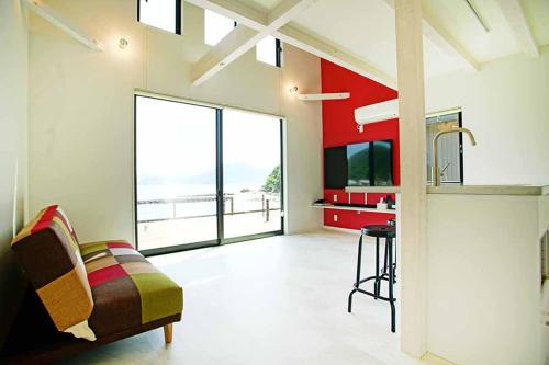 a living room with a couch and a kitchen with a view at Rainbow Village（レインボーヴィレッジ） in Mihama