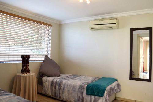 a bedroom with a bed and a mirror and a window at Phoenix Lodge - Ramsgate KwaZulu Natal in Margate