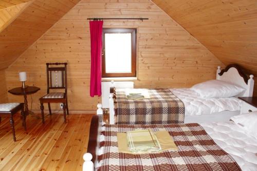 um quarto com uma cama num chalé de madeira em Agroturystyka Żubr em Siemianówka