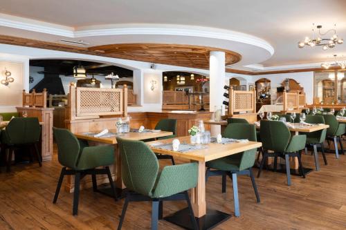 a restaurant with wooden tables and green chairs at Sepp & Hannis Suiten im Dorf in Neustift im Stubaital