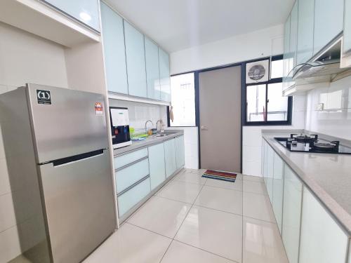 a kitchen with white cabinets and a stainless steel refrigerator at Lion Home in Seri Kembangan