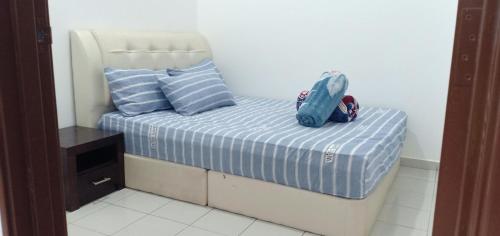 um pequeno quarto com uma cama com lençóis e almofadas azuis em HOMESTAY BUDGET MASJID TANAH PERDANA em Masjid Tanah