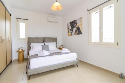 a white bedroom with a bed and two windows at Daphne's place in Vívlos