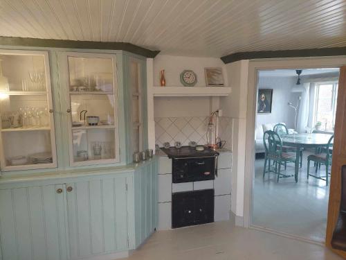 a kitchen with a stove and a dining room with a table at Vadstena semesterlägenhet in Vadstena