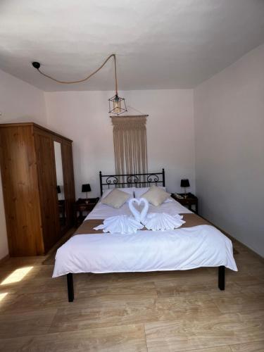 a bedroom with a large bed with white sheets at Taxiarchis in Symi