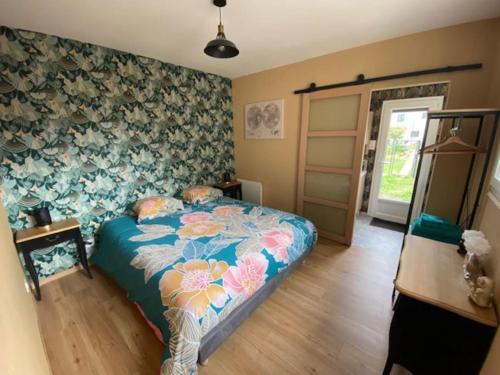 een slaapkamer met een bed met bloemenbehang bij La Maison Passageon, Tout confort in Châteauroux