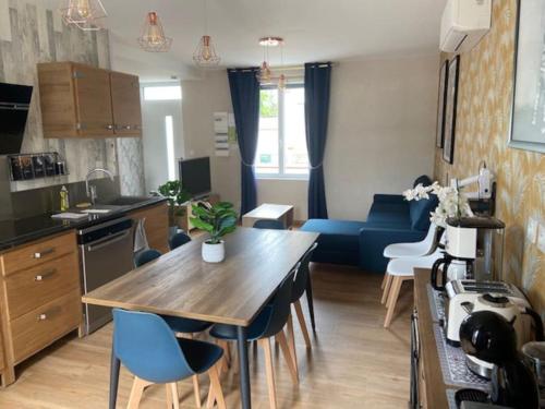 een keuken en een woonkamer met een tafel en een blauwe bank bij La Maison Passageon, Tout confort in Châteauroux