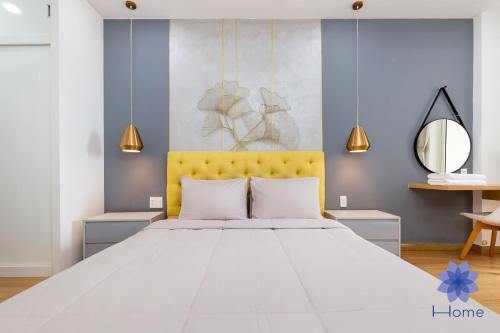 - une chambre avec un grand lit blanc et une tête de lit jaune dans l'établissement iHome Furnished Apartments in Orchard Park View Building with Free Gym & Pool, Airport Pick-Up Service, à Hô-Chi-Minh-Ville
