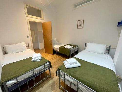 Cette chambre comprend 2 lits et une chaise. dans l'établissement The Falcon by condokeeper, à Londres