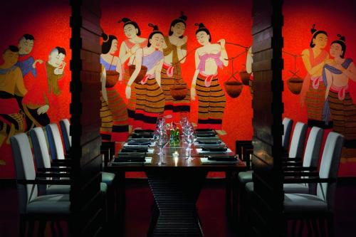 a table in a room with a painting of women at Phulay Bay, A Ritz-Carlton Reserve in Tab Kaek Beach