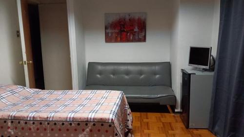 1 dormitorio con cama, sofá y TV en Donde Gabriel en Chillán