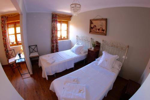 Cette chambre comprend 2 lits, une table et des fenêtres. dans l'établissement Casa Rural Melitón, à Povedilla