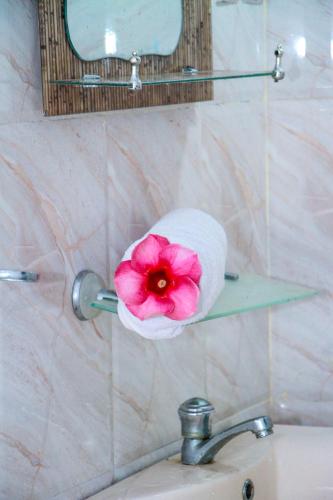 a toilet paper holder with a pink flower on a bathroom sink at Sigiri Nirwana Lodge in Sigiriya