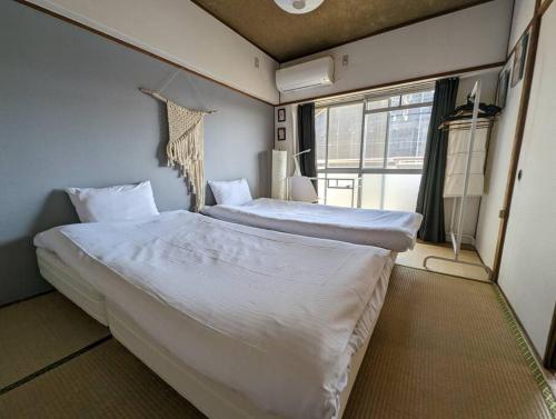 a bedroom with a large bed with white sheets at 【豊和マンション稲荷302号室】伏見稲荷駅徒歩３分！Free Wifi付のお宿！ in Kyoto
