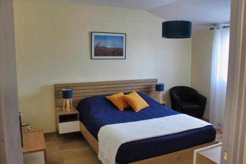 a bedroom with a blue bed and a chair at La Casa Del Pou classée 3 étoiles proche Céret et Thuir Terrain 800m2 Parking privé in Llauro