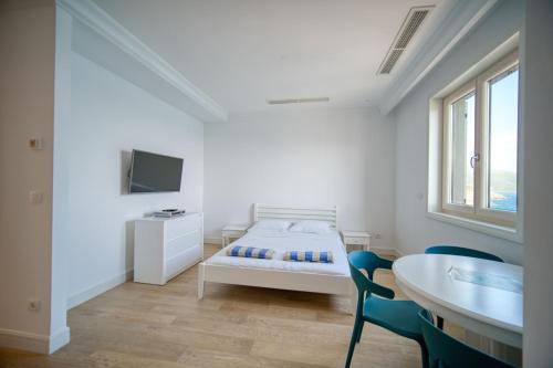 um quarto branco com uma cama, uma mesa e cadeiras em Studio Apartment By 2bhome em Radovići