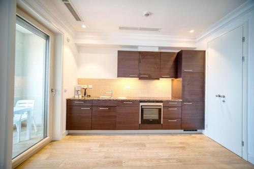 uma cozinha com armários de madeira e uma grande janela em Studio Apartment By 2bhome em Radovići