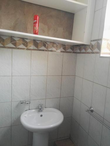 a bathroom with a sink and a red can on a shelf at The Stone Guest House in Teyateyaneng