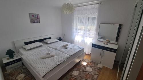a white bedroom with a bed and a mirror at Apartment Dolic in Livno