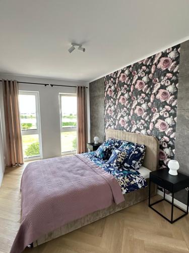 a bedroom with a large bed with a floral accent wall at Apartament Widokowy Zamkowa in Tczew