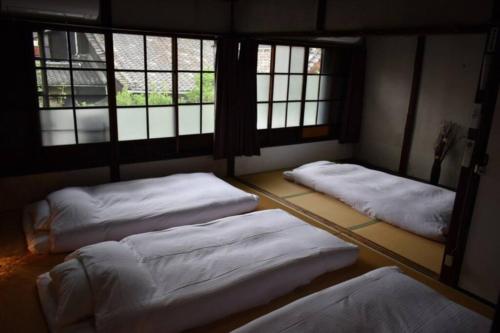 three beds in a room with windows at 【利灸ゲストハウス】3 mins walk to Kyoto station! Unique house！ in Kyoto