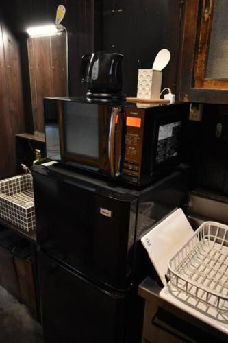 a microwave sitting on top of a black refrigerator at 【利灸ゲストハウス】3 mins walk to Kyoto station! Unique house！ in Kyoto