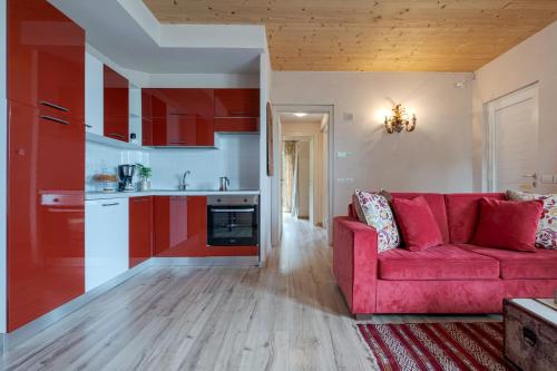 a living room with a red couch and a kitchen at La Rosa Gialla Bio Apartments & rooms in Barolo