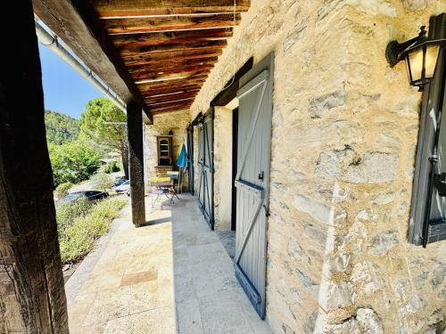 a stone building with a door and a wooden roof at Maison en pierre, piscine, spa in Buis-les-Baronnies