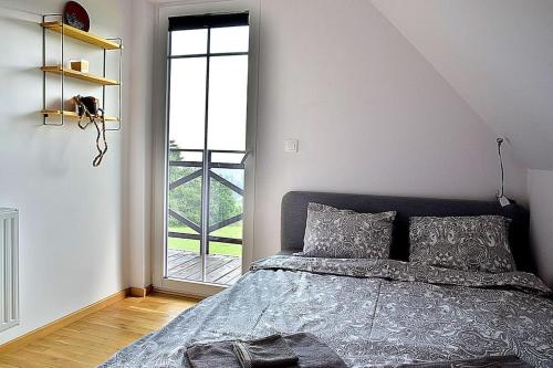 a bedroom with a bed and a large window at Wyspa Zdarzeń - klimatyczny dom w sercu natury! in Żmiąca