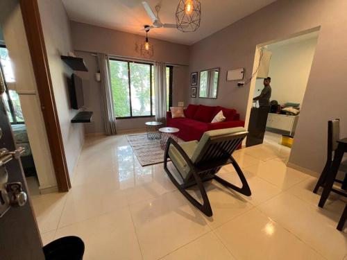een woonkamer met een rode bank en een stoel bij Pali Carters Building 102, 20th Road, Khar West by Connekt Homes in Mumbai