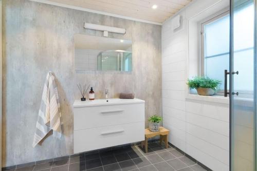 La salle de bains est pourvue d'un lavabo blanc et d'un miroir. dans l'établissement Cabin in Malangen, à Mestervik