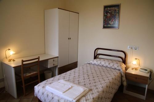 Habitación pequeña con cama, escritorio y mesa. en Hotel Madonna di Loreto en Loreto