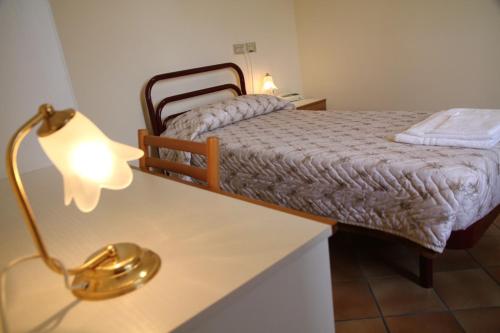 a bedroom with a bed and a table with a lamp at Hotel Madonna di Loreto in Loreto