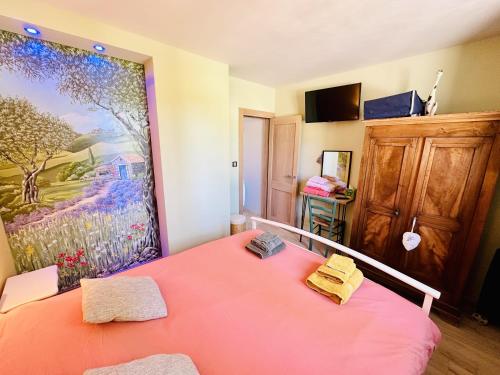 a bedroom with a pink bed with a painting on the wall at Maison en pierre, piscine, spa in Buis-les-Baronnies