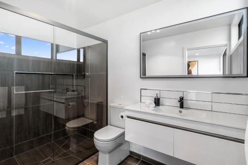 een badkamer met een toilet, een wastafel en een spiegel bij A Remarkable Stay - Jack's Point Holiday Home in Queenstown