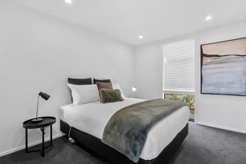 een witte slaapkamer met een groot bed en een raam bij A Remarkable Stay - Jack's Point Holiday Home in Queenstown