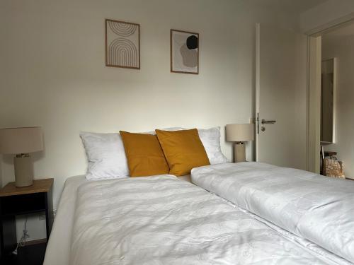 プリーン・アム・キームゼーにあるSeeapartmentの白いベッド1台(ベッドルームにオレンジの枕2つ付)