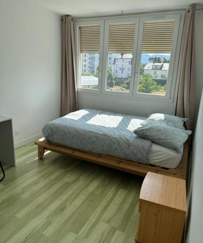 une chambre avec un lit avec une fenêtre et une table dans l'établissement Appartement T4 des jardins, à Chambéry