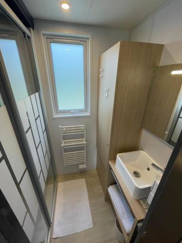 ein kleines Bad mit einem Waschbecken und einem Fenster in der Unterkunft CAMP'HOTEL in Mamers