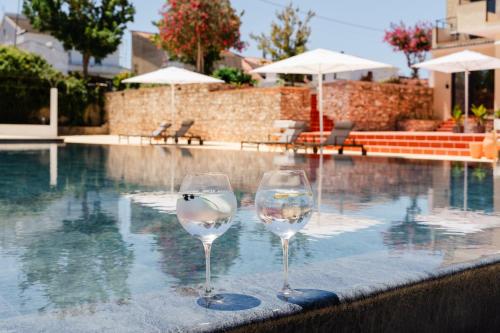 two wine glasses sitting next to a swimming pool at VILLA DOS R'S in Avis