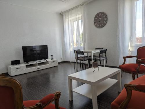 a living room with a tv and a table and chairs at Le Thannois - appartement 2 chambres, salon, cuisine équipée, parking et wifi gratuit in Mulhouse