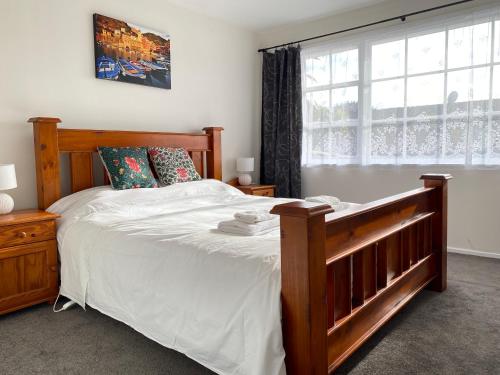 a bedroom with a large wooden bed with a window at Ali Motel in Auckland