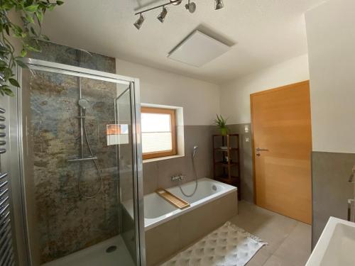 a bathroom with a shower and a bath tub at Magic Birkenweg in Scharnstein